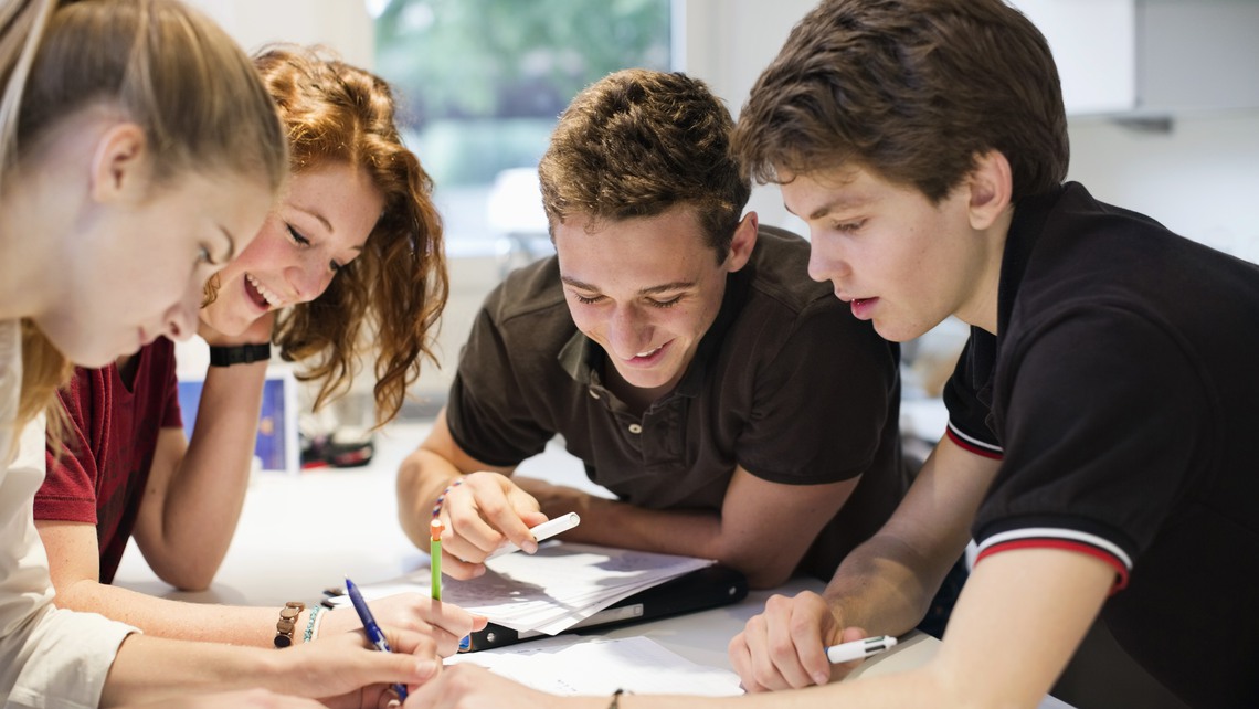 Happy young students studying together at table