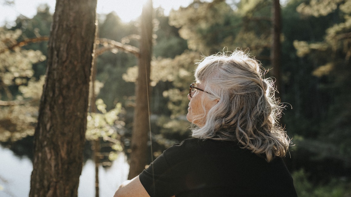 Kvinnlig pensionär sitter vid sjö