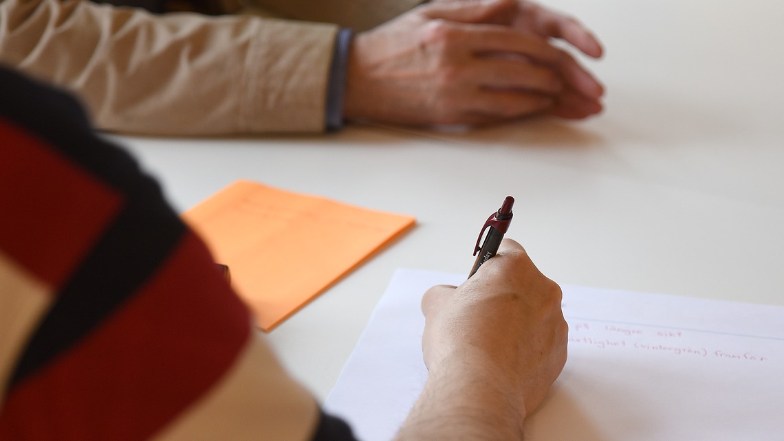 Personer som sitter vid ett bord och skriver.
