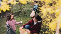 Happy daughter helping mother in collecting waste at backyard