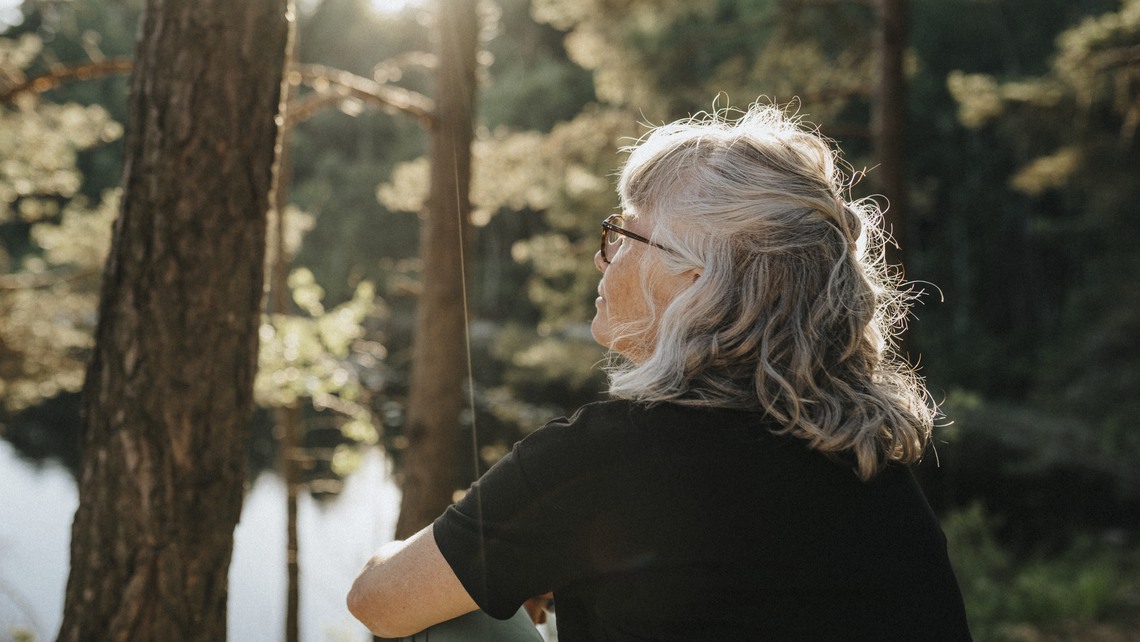 Kvinnlig pensionär sitter vid sjö