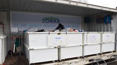 Vit container med skräp uppställd på en parkeringsplats.