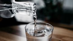 En kanna med vatten häller upp dricksvatten i ett glas.