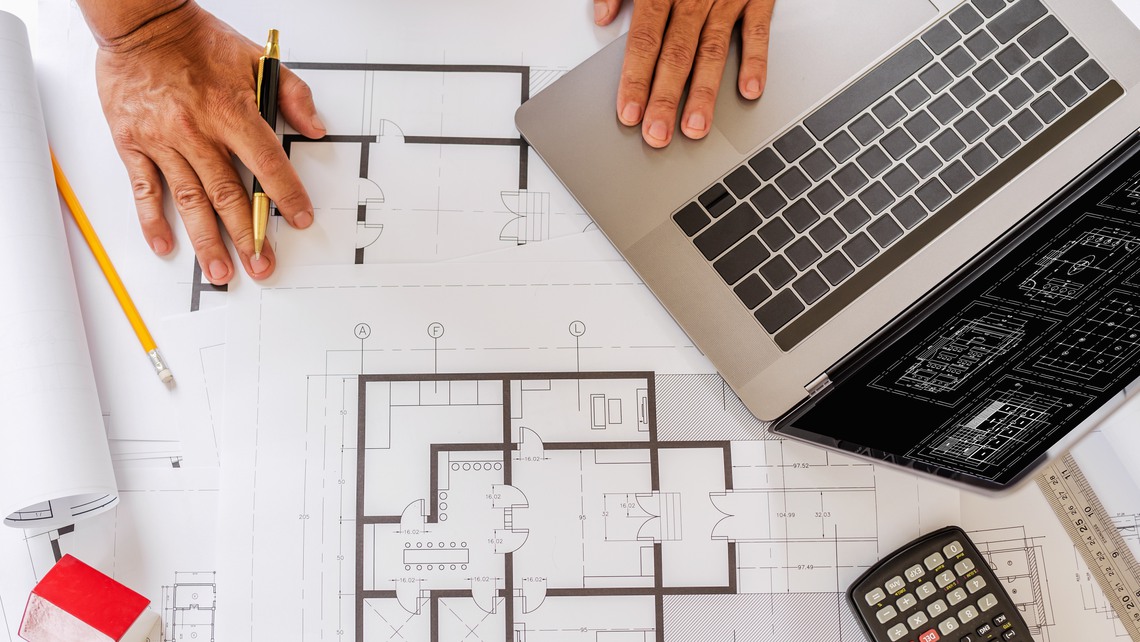 Blueprints of designer and engineers working at architects office desk.