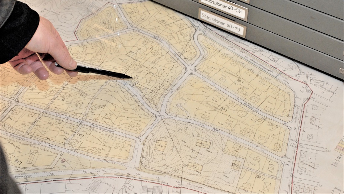 En hand pekar med en penna p&aring; en karta.