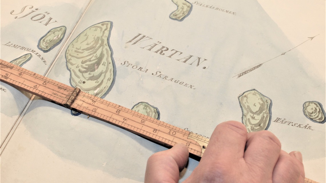 En linjal ligger &ouml;ver en karta.